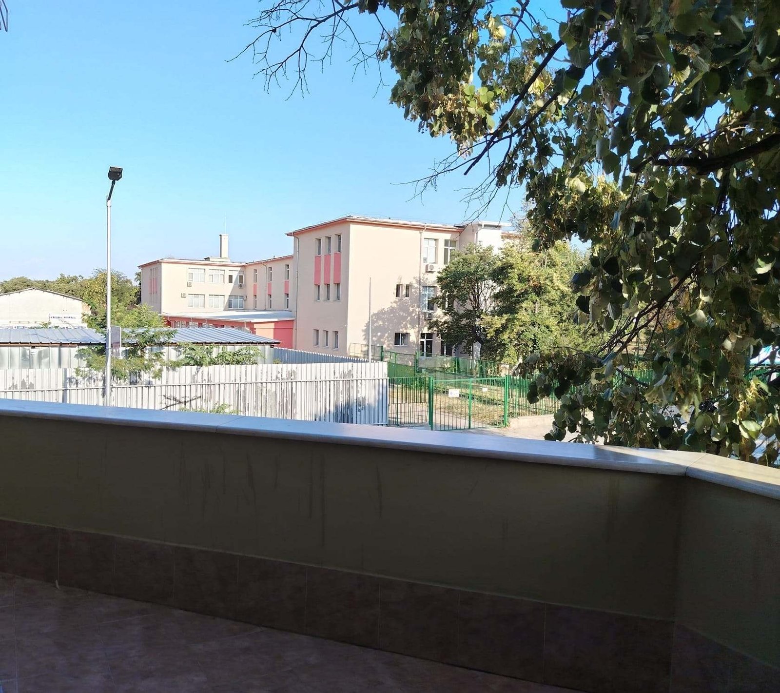Изглед от терасата към зелени дървета и сгради